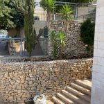 גינה עם קירות אבן, צמחייה ועצים