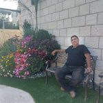 גנן יושב על ספסל ליד פרחים