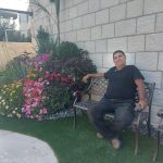 גנן יושב על ספסל ליד גינה