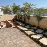חצר עם שבילים מסלעים וצמחייה מטופחת