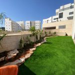 גינה מעוצבת עם דשא סינתטי ועציצים