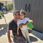 גנן מחזיק ילדה עם דלי בגינה