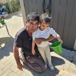 גנן מחזיק ילד עם דלי ירוק,