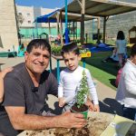 ילד ומבוגר עם צמח במיכל גינון