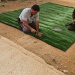 איש מתקין דשא סינטטי בשטח פתוח