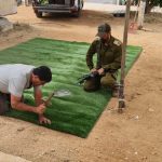 איש מתקין דשא סינתטי עם כלי