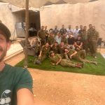 קבוצה של חיילים יושבת ומחייכת בחצר