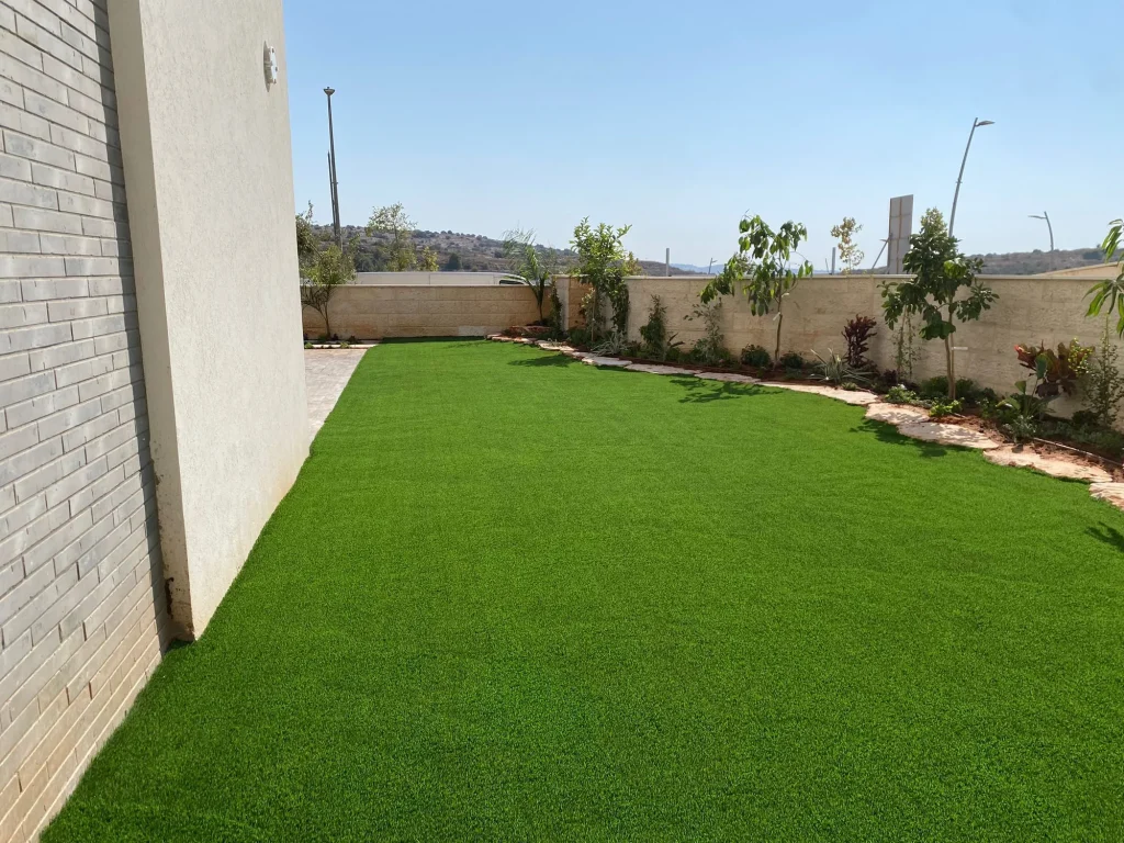 מבט לאורך הבית על הדשא הסינטטי והערוגה שלאורך הקיר