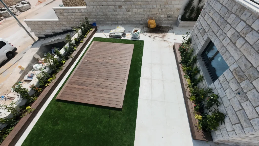 משטח דק על דשא סינטטי בין אדניות שתולות, מבט מלמעלה