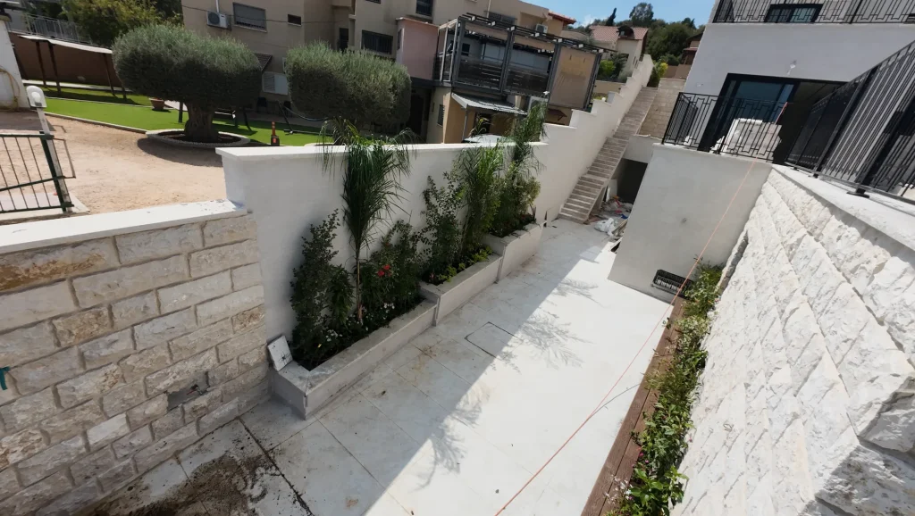 אדנית שתולה לאורך קיר אבן בכניסה לבית