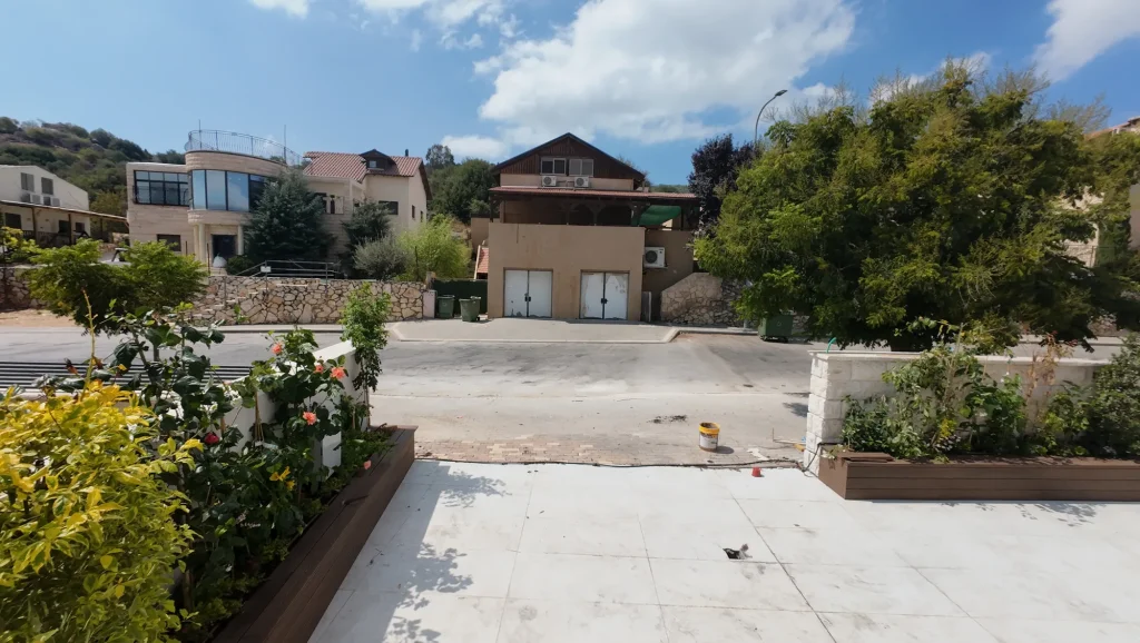 אדניות עץ שתולות בשיחים פורחים בחזית הבית