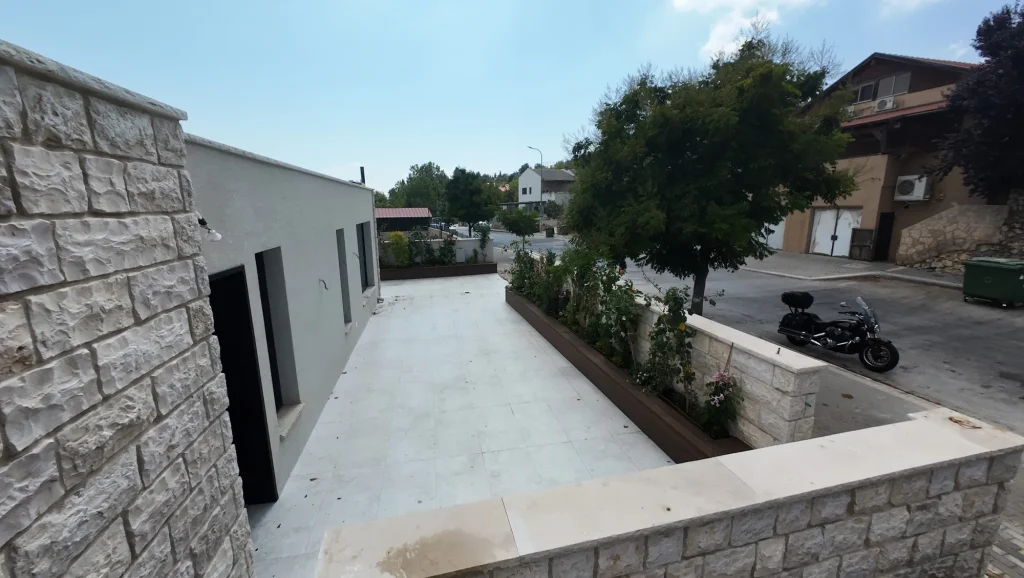 אדנית שתולה לאורך קיר הבית בצד החצר