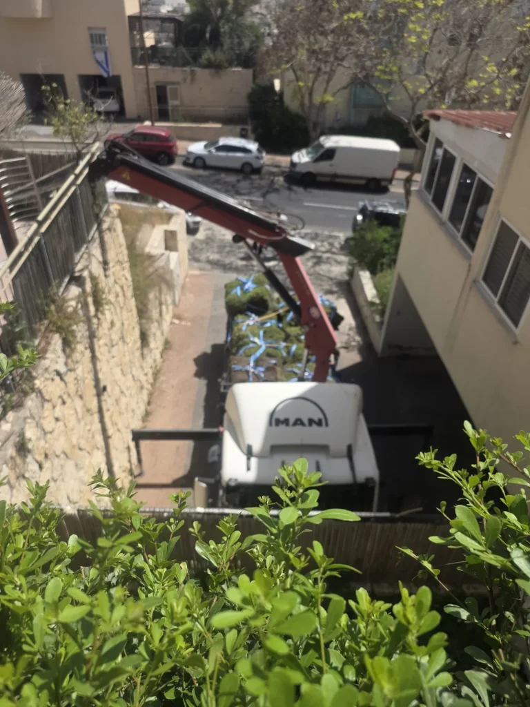 משאית מנוף בסמטה שמתחת לחצר לפני הנפת הדשא
