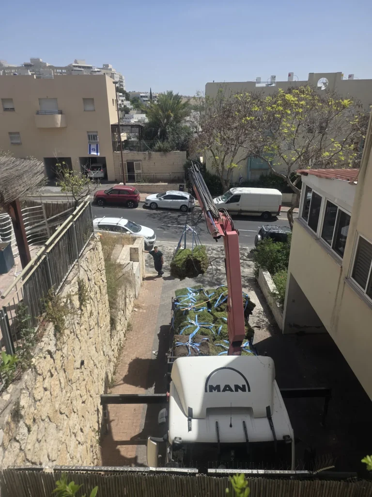 זרוע המנוף מעל קיר האבן במהלך הנפת גלילי הדשא